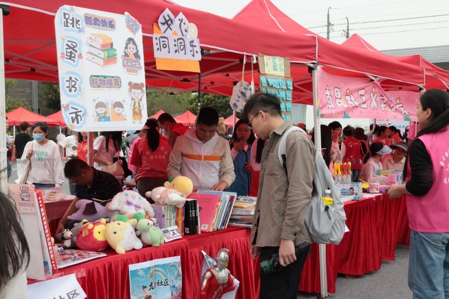 Visitors browsing charity goods at a Xixiang community booth